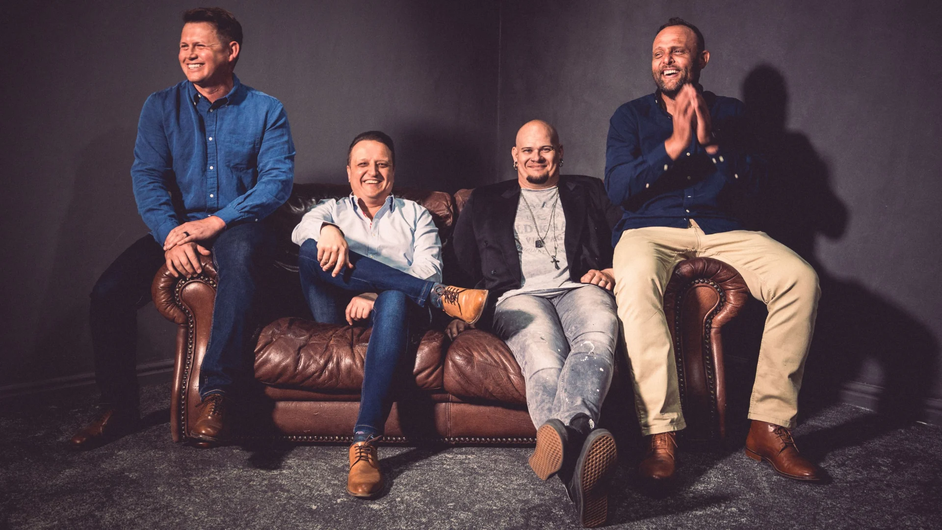 The Heritage Worship band seated together on a leather couch.